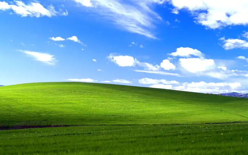 A green field with blue sky and clouds